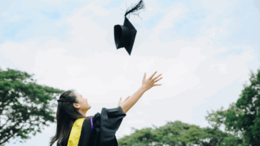 A woman throwing a graduation cap in the air.