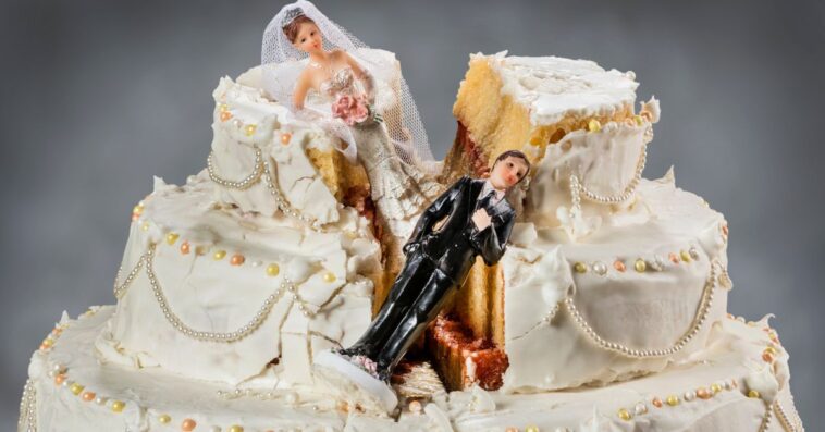 Bride and groom figurines collapsed in a ruined wedding cake.