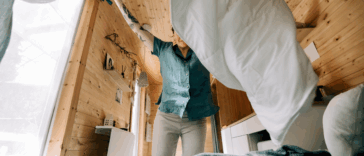 A woman throwing a sheet over a bed.