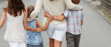 A woman walking with three children.