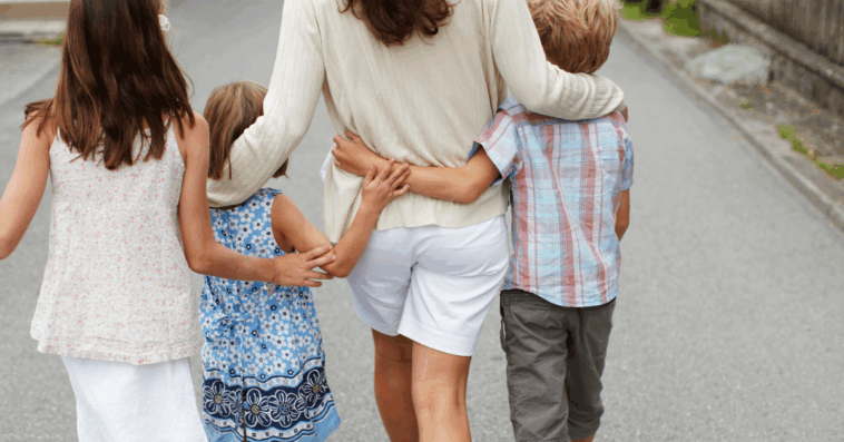 A woman walking with three children.
