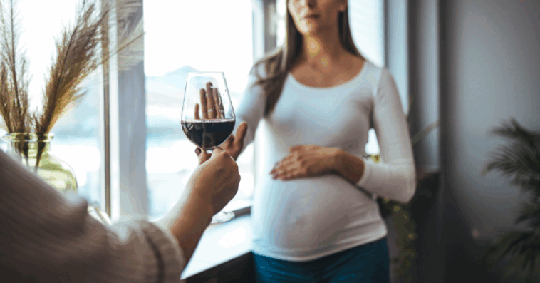 pregnant woman refusing a glass of wine