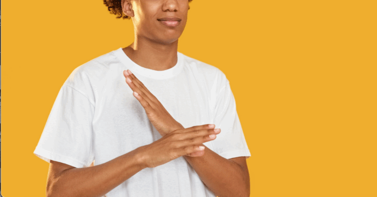 A man in front of a yellow background with his arms crossed.
