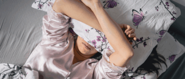 A woman lying in bed with a pillow covering her eyes.
