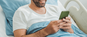 Man scrolling through his phone in a hospital bed