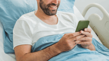 Man scrolling through his phone in a hospital bed