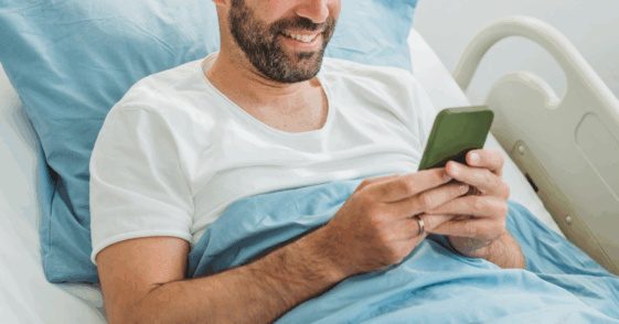 Man scrolling through his phone in a hospital bed
