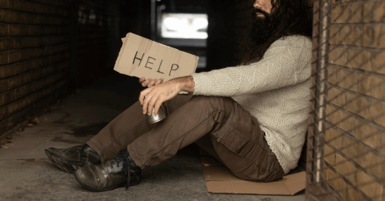 unhoused man in tunnel entrance