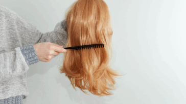 a woman combing a wig she's holding in her hand.