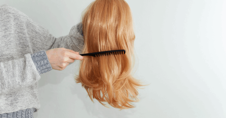 a woman combing a wig she's holding in her hand.