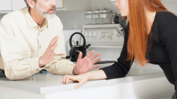 older man and younger woman arguing in kitchen