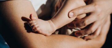 Close up of a loving young father carrying his newborn baby daughter in arms. Bonding moment of father and daughter.