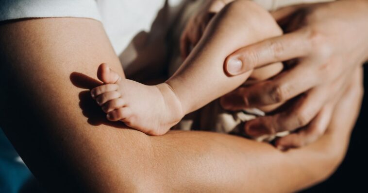 Close up of a loving young father carrying his newborn baby daughter in arms. Bonding moment of father and daughter.