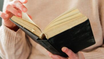 Close-up of a woman's hands turning the pages of a book.