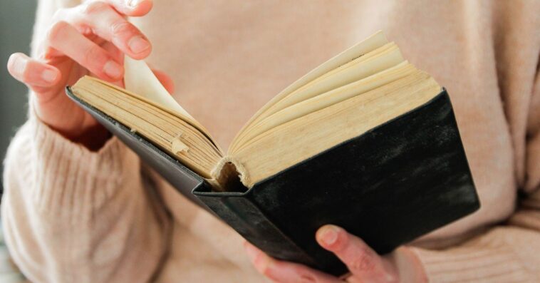Close-up of a woman's hands turning the pages of a book.