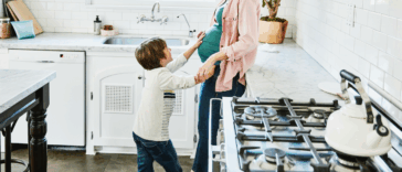 A little boy patting the stomach of a pregnant woman.