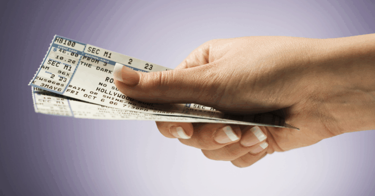 A person holding a pair of concert tickets