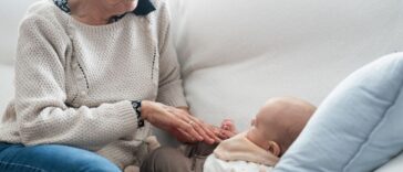 Grandmother caressing her newborn grandchild on the sofa: intergenerational connection and tender family moments.