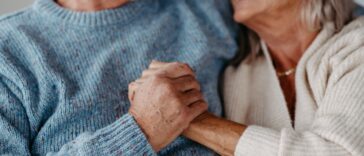 Close-up of senior couple cuddling and holding hands in their home.