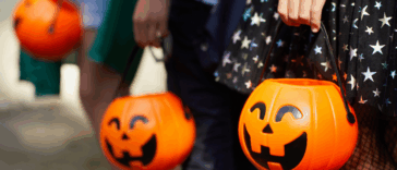 Three children holding pumpkin trick or treat buckets.