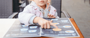 A Child sitting at a table looking at a menu.