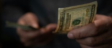 Close-up of man's hand passing a twenty dollar bill.