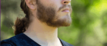A man with a ponytail standing in profile.