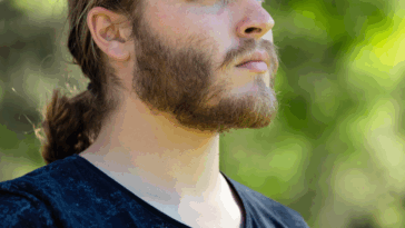 A man with a ponytail standing in profile.