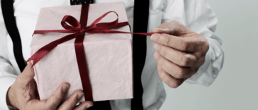 A man holding a present pulling on the ribbon.
