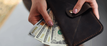 A woman pulling cash bills out of a wallet.