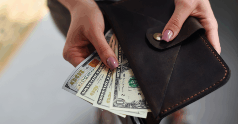 A woman pulling cash bills out of a wallet.