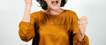 An older woman shaking her hands with her mouth open.