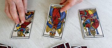 A pair of man's hands deals out tarot cards.
