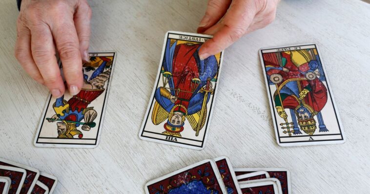 A pair of man's hands deals out tarot cards.