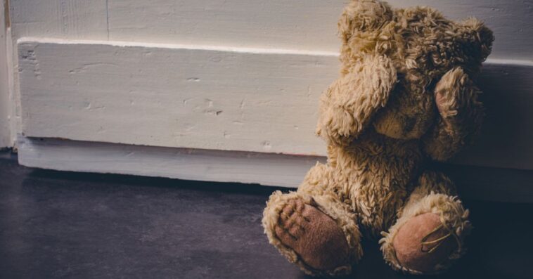 Abandoned Teddy Covering His Eyes, Sitting At A Door.