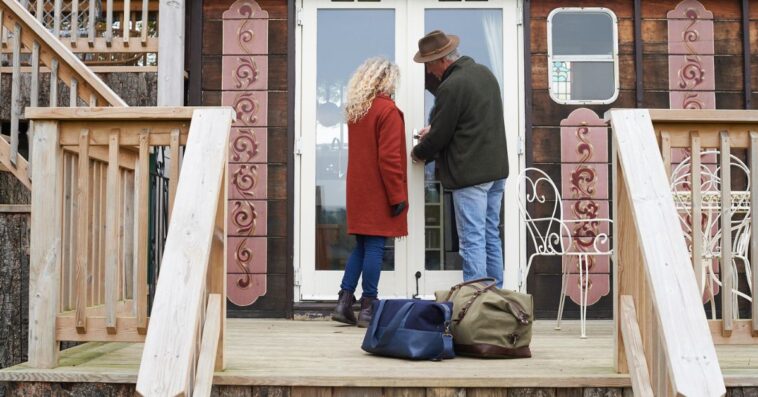 Mature couple arriving for a glamping weekend at an eco lodge.They are unlocking the door on arrival.