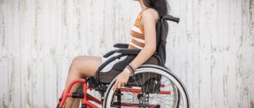 Side view of a disabled teenage woman in a wheelchair outdoors.