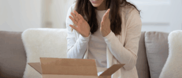 A woman sitting in front of an open cardboard box.