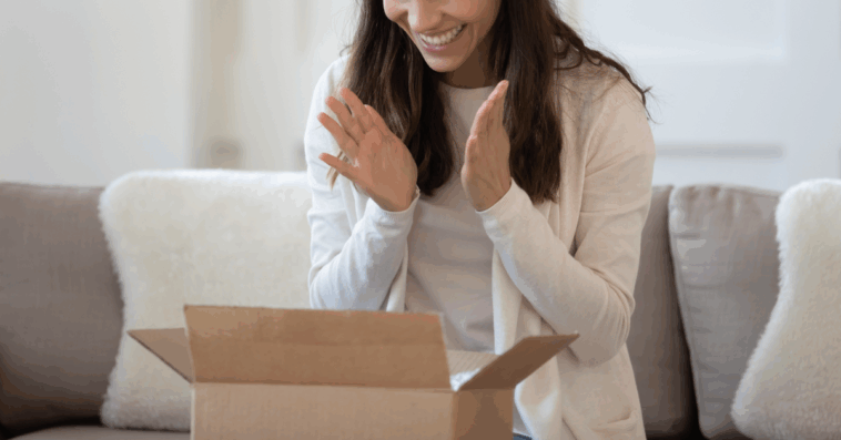 A woman sitting in front of an open cardboard box.