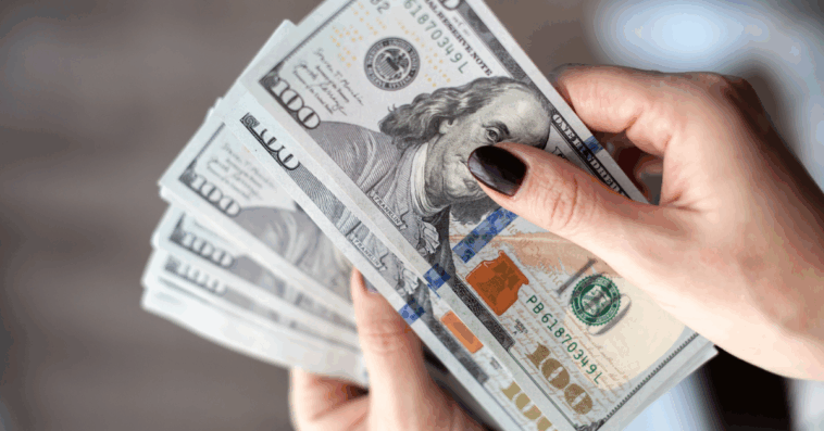 woman holds stack of $100 bills