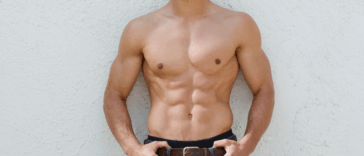 shirtless man posing in front of a white wall