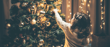 child adding decoration to Christmas tree