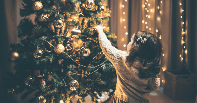 child adding decoration to Christmas tree