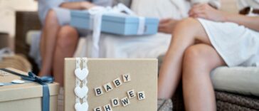Close-up of a present marked 'baby shower,' with attendees in the background.
