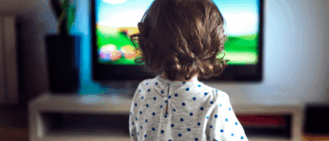 A Toddler child in front of a television screen.