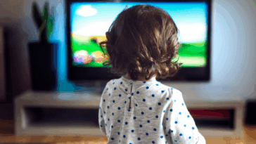 A Toddler child in front of a television screen.