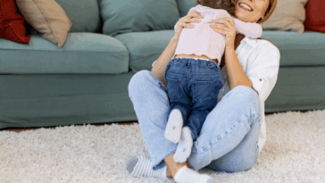 A woman sitting on the floor holding a toddler.
