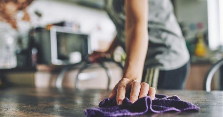 Close-up of a hand with a rag wiping a table.
