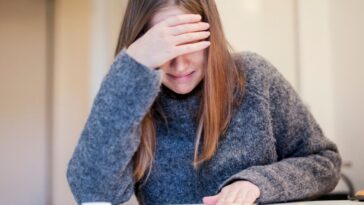 A crying young woman, covers her eyes.