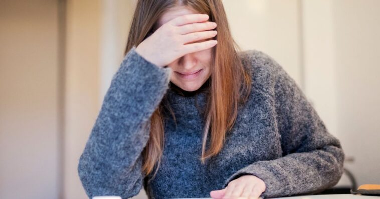 A crying young woman, covers her eyes.